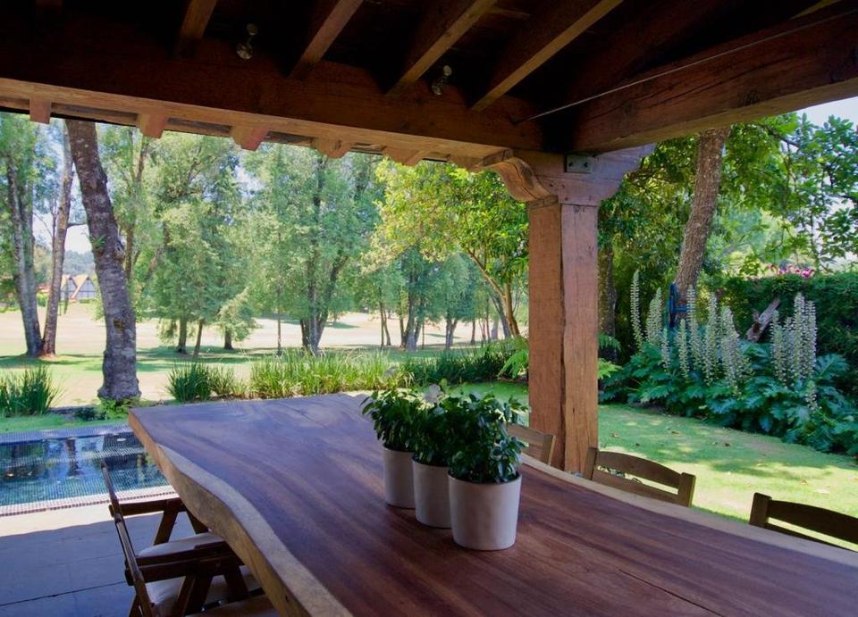 Terraza techada con columna y zapata de madera frente al jardín