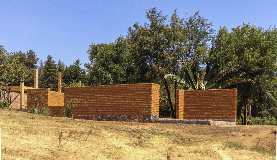 Muros de tierra del Rancho Sustentable entre árboles