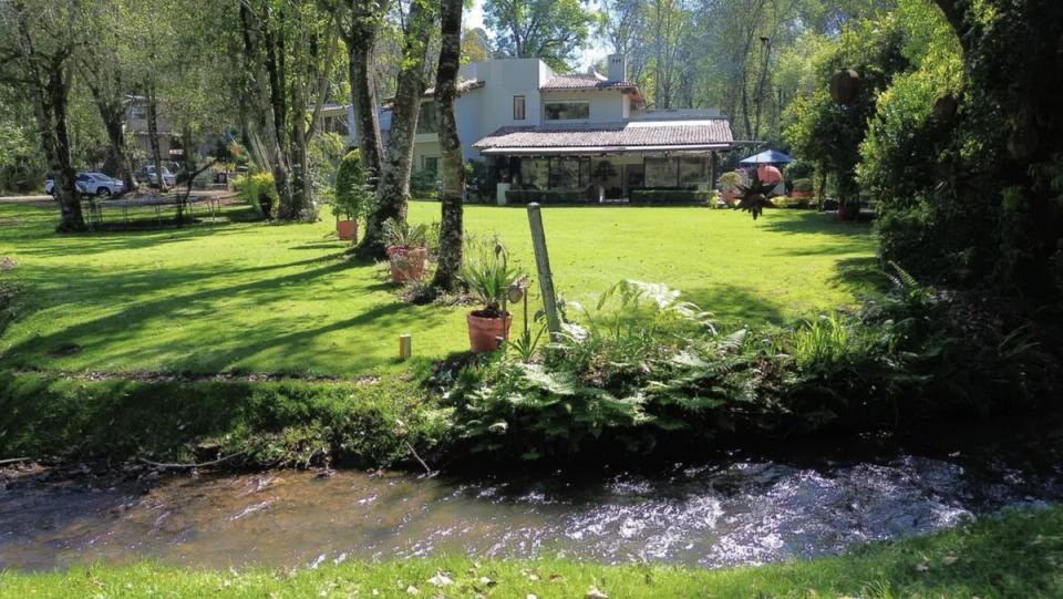 La casa al fondo del jardín, con un arroyo en primer plano