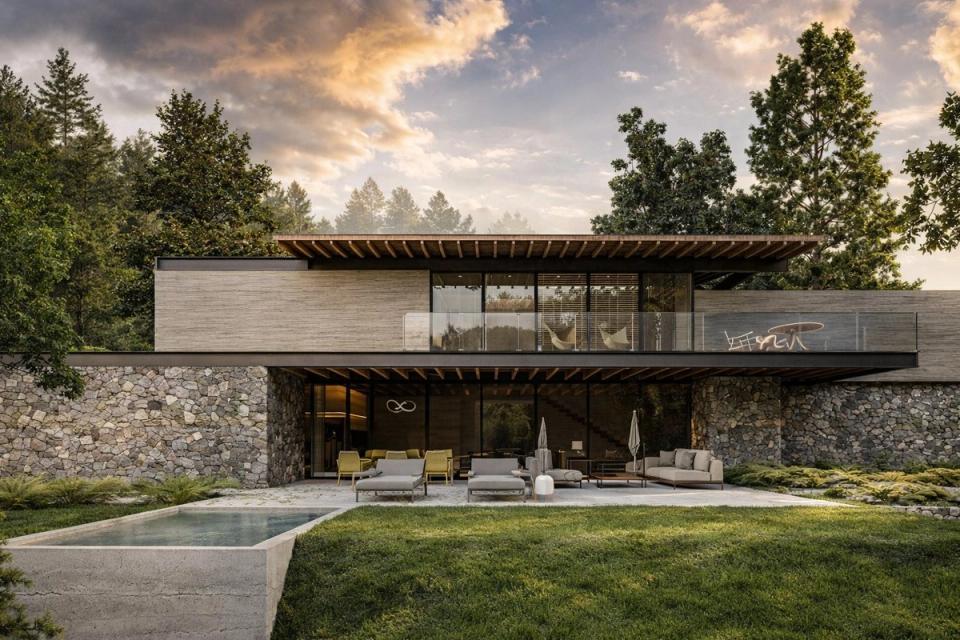 Casa con muros de piedra, terraza de cristal y alberca al atardecer