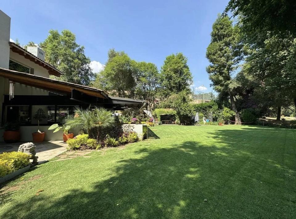 Jardín junto a la casa con aleros de madera y techos de teja