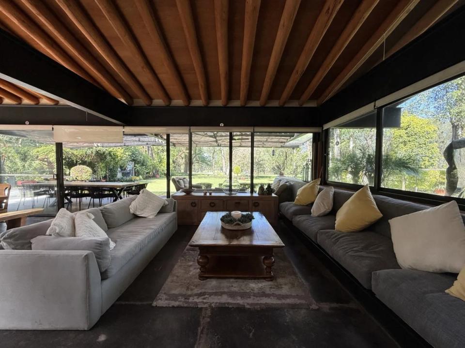 Sala con ventanales hacia el jardín bajo vigas de madera