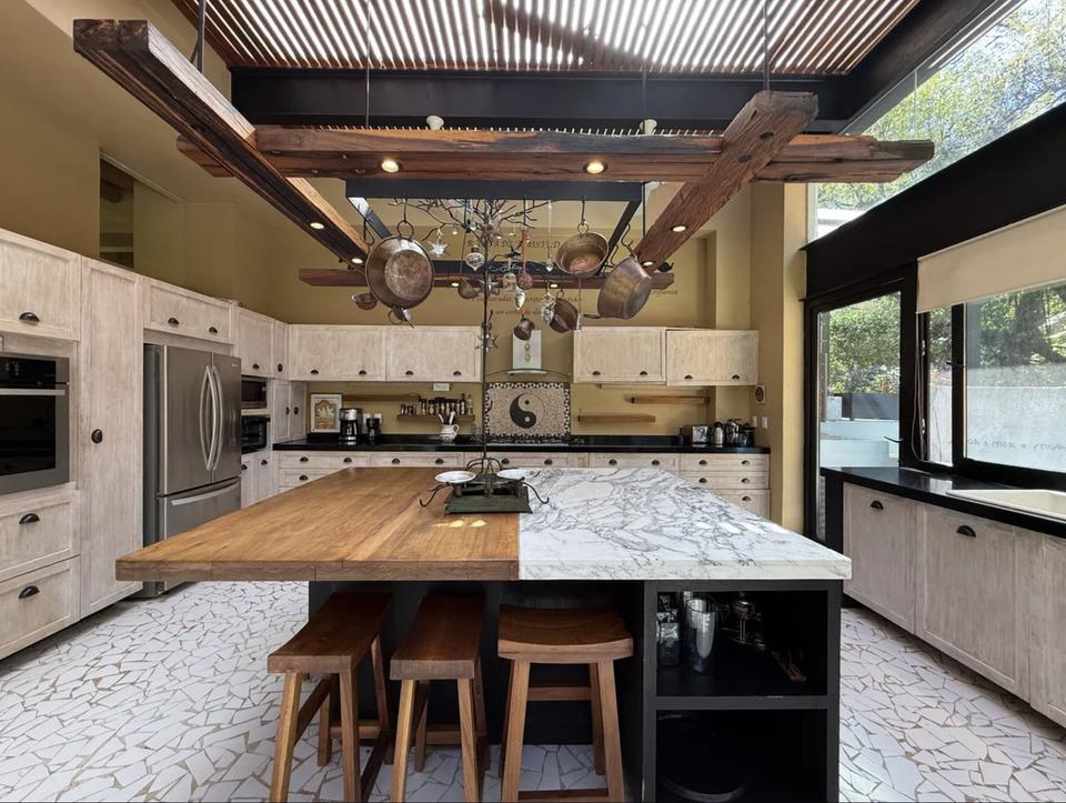 Isla de cocina mitad madera y mitad mármol sobre piso de pedacería