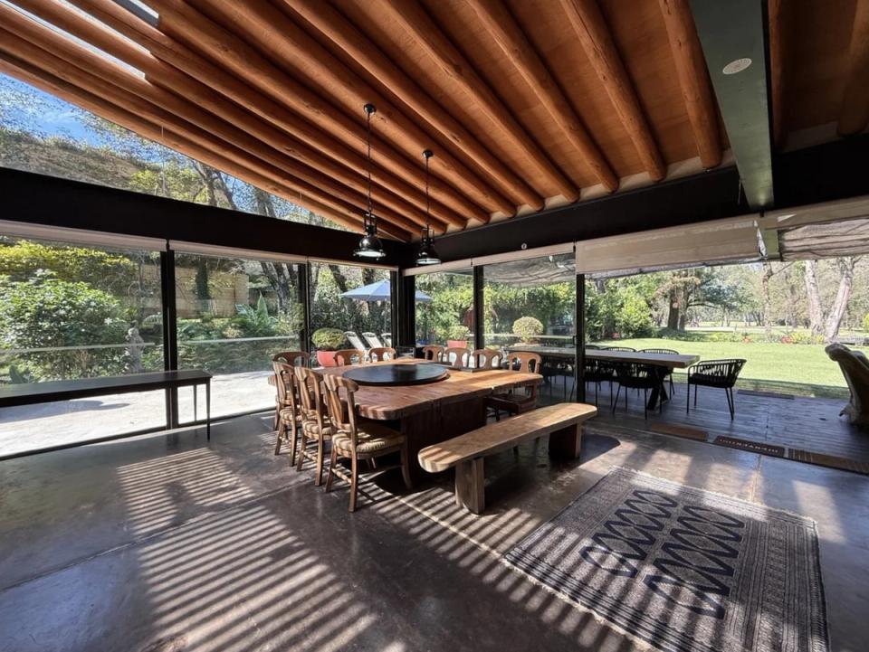 Comedor entre muros de cristal con franjas de sol sobre el piso