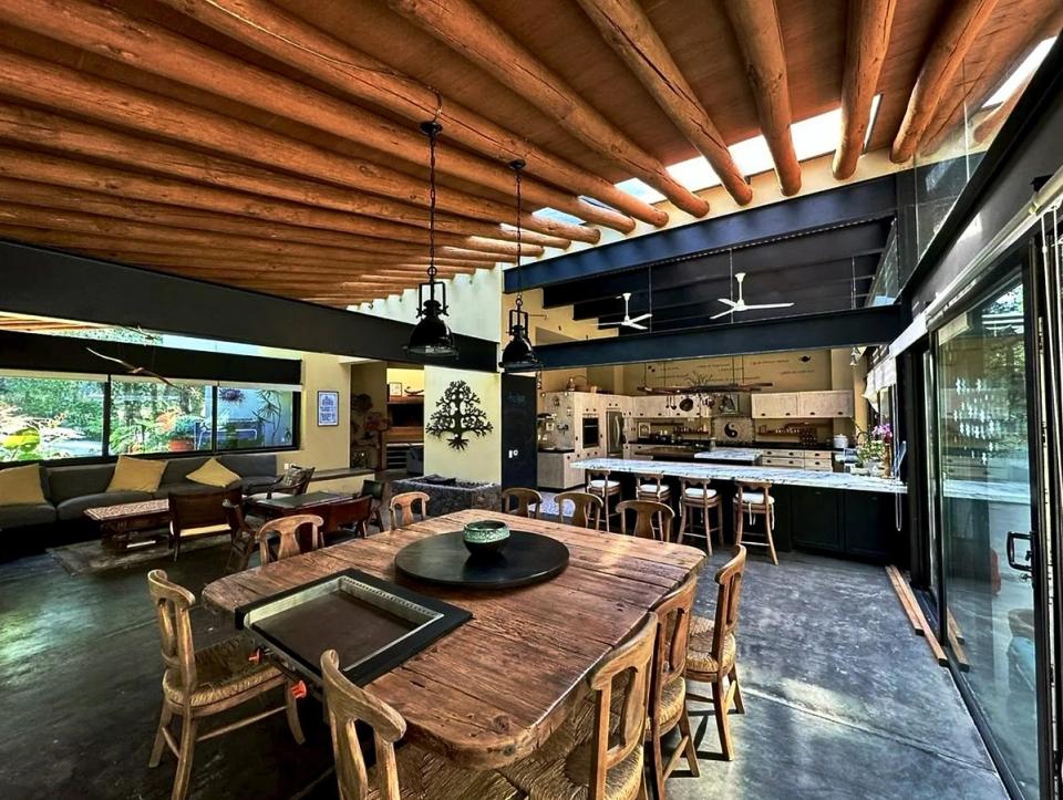 Comedor, cocina y sala integrados bajo vigas de madera