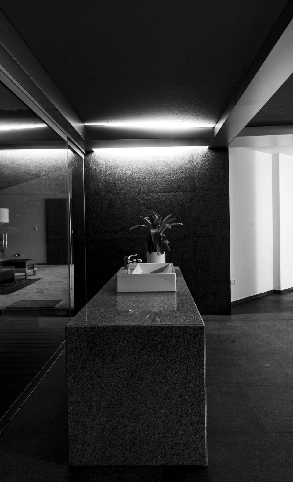 Lavabo sobre un bloque de piedra con luz indirecta, en blanco y negro