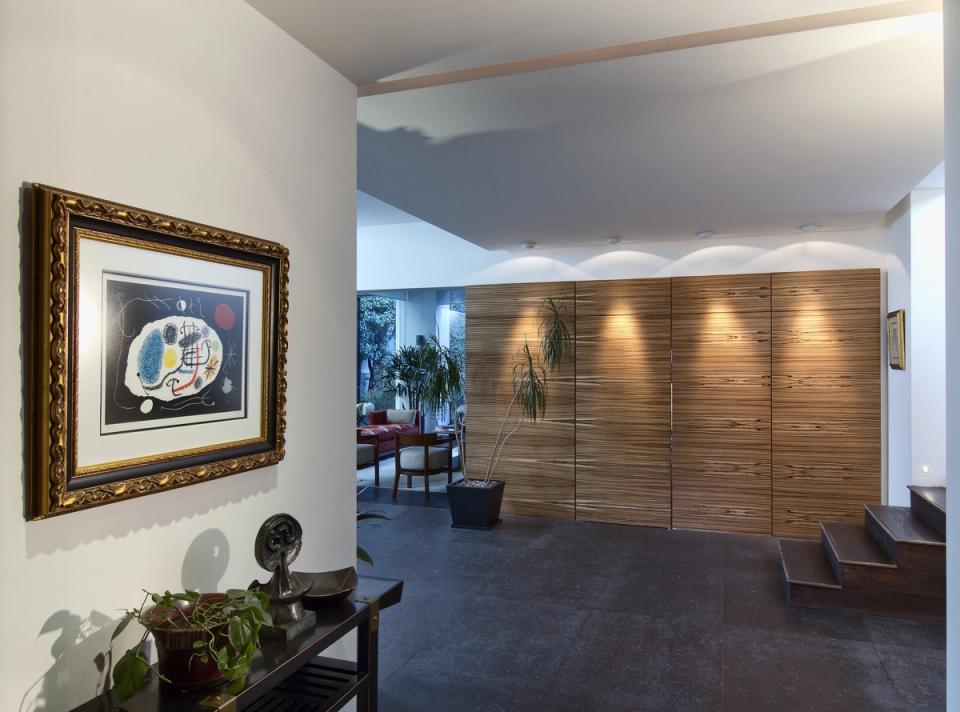 Vestíbulo con muro de madera iluminado y vista a la estancia