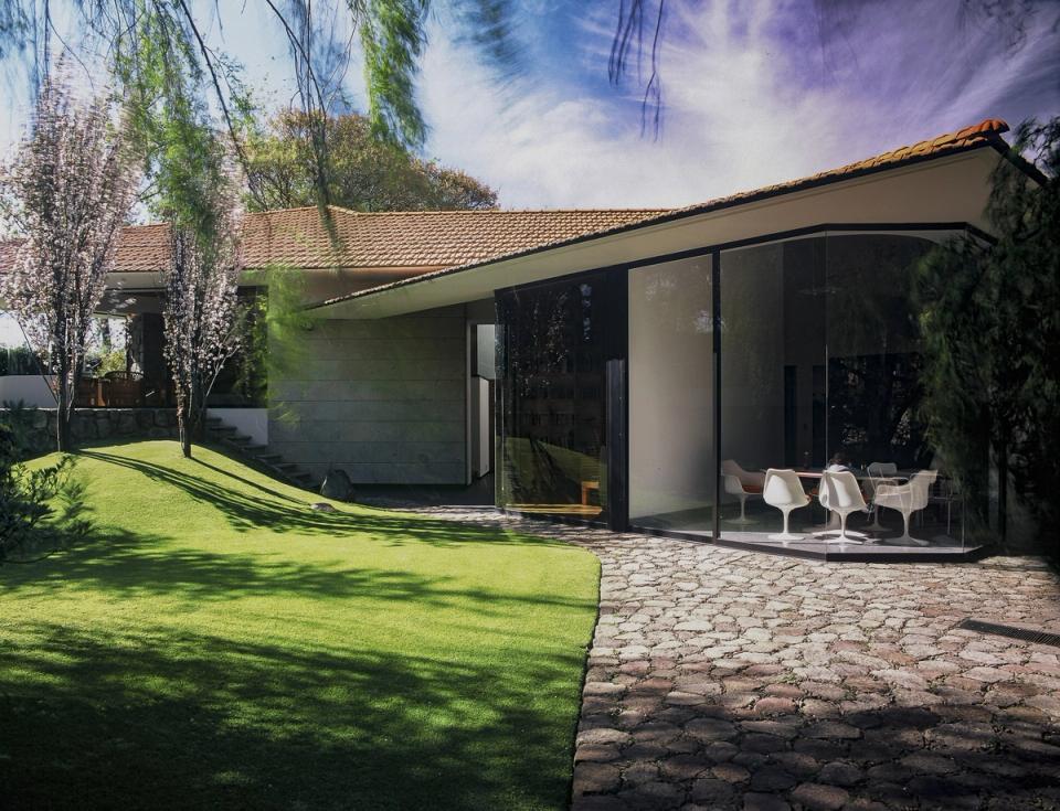 Casa con muro de cristal curvo frente al jardín y camino de piedra