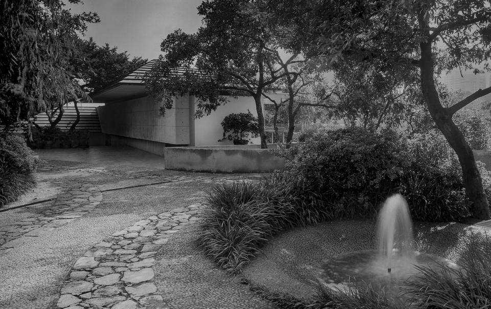Jardín de acceso con fuente y camino de piedra, en blanco y negro