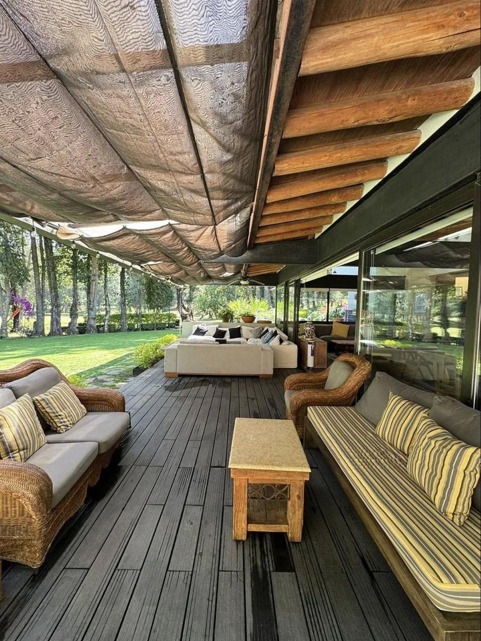 Terraza bajo toldos de tela y vigas de madera, abierta al jardín