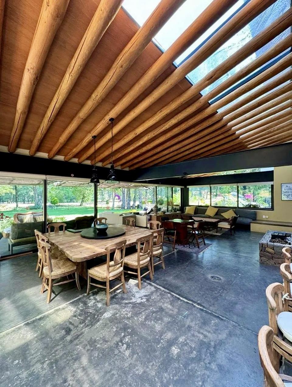 Comedor bajo tragaluces entre vigas de madera, abierto al jardín