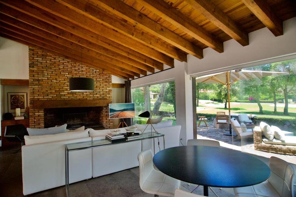 Sala y comedor junto a la chimenea de ladrillo con vista a la terraza