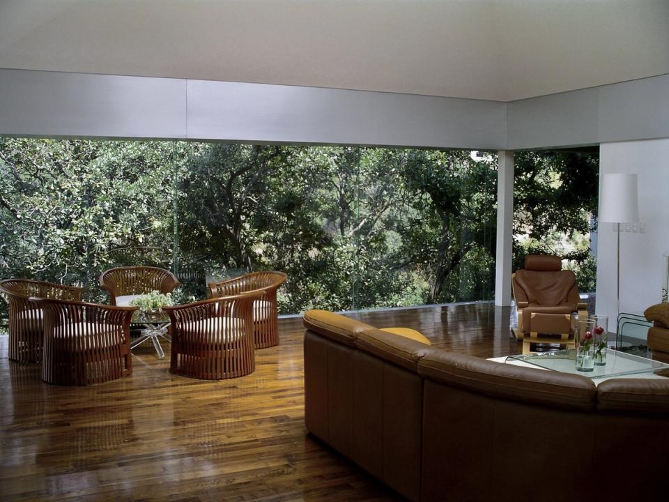 Sala con muros de cristal hacia la arboleda y piso de madera