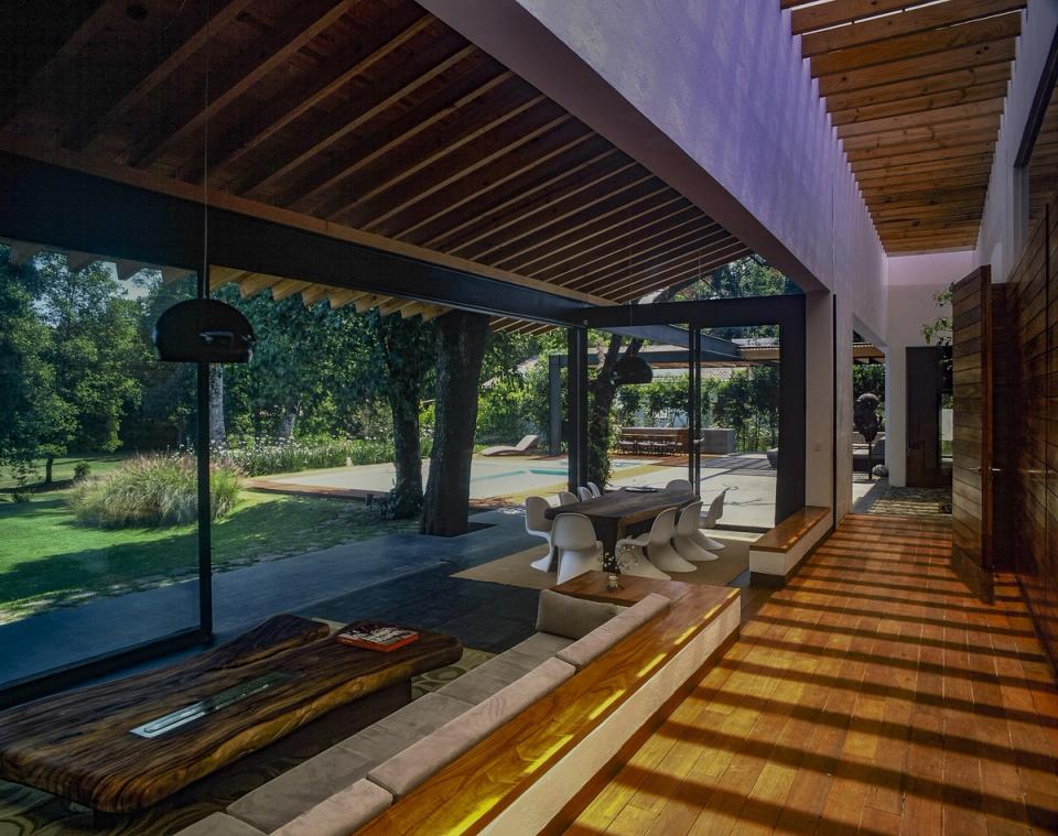 Estancia abierta al jardín bajo techo de vigas de madera