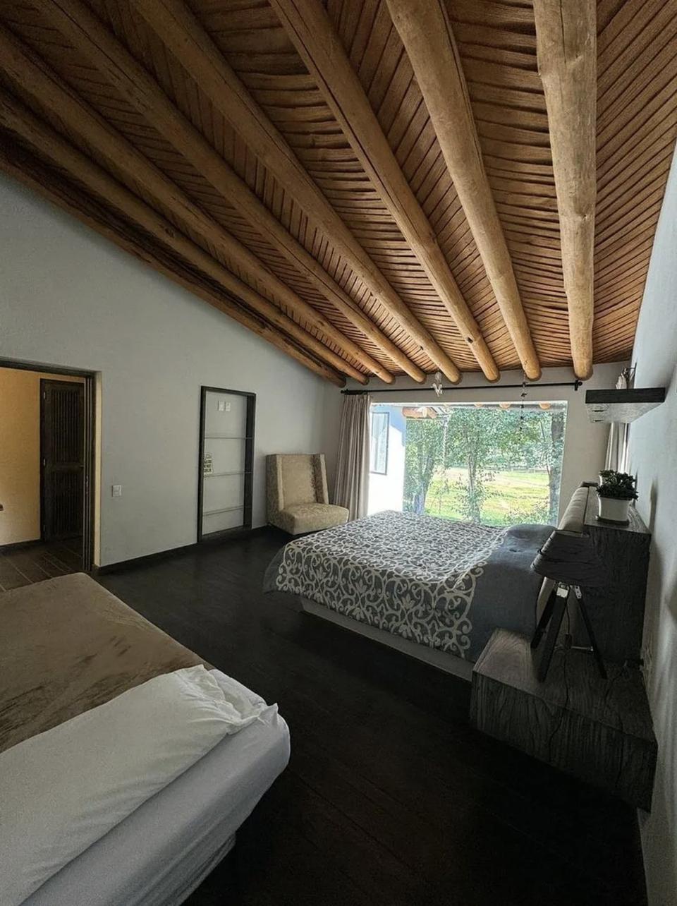 Recámara con techo inclinado de vigas y ventana hacia el jardín