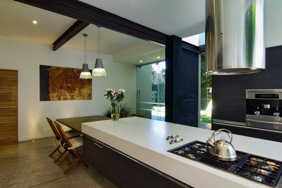 Isla de cocina con viga de acero y puerta de cristal al jardín