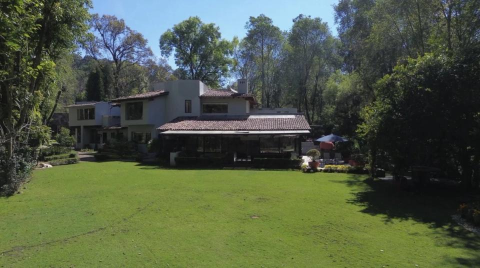 Vista completa de la casa desde el jardín, rodeada de árboles