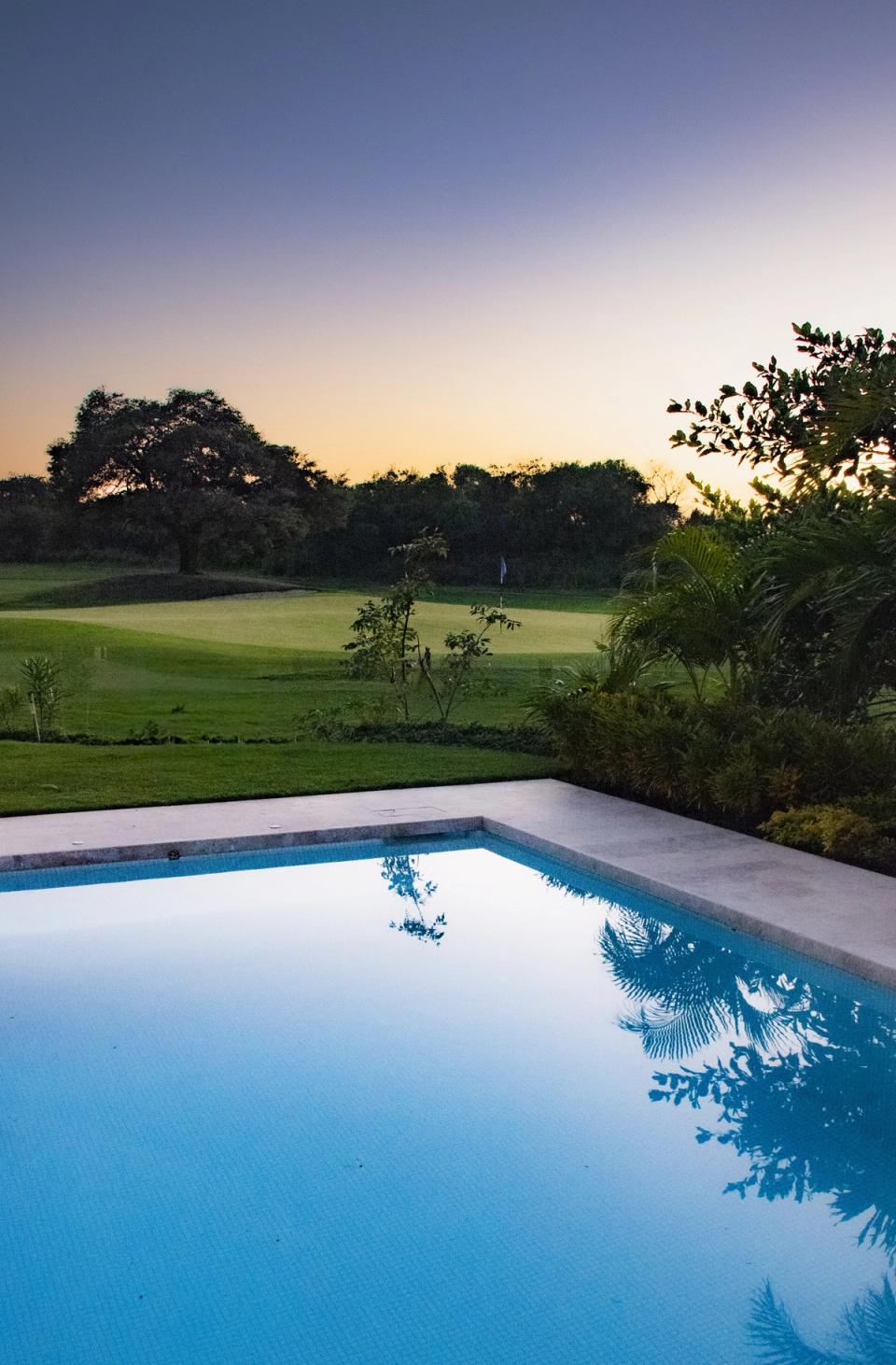 Alberca al atardecer con vista al campo de golf
