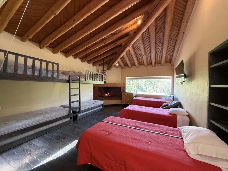Cuarto de literas con chimenea en esquina y colchas rojas