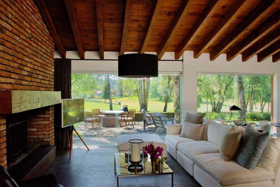 Sala con vigas de madera y ventanales abiertos hacia la terraza