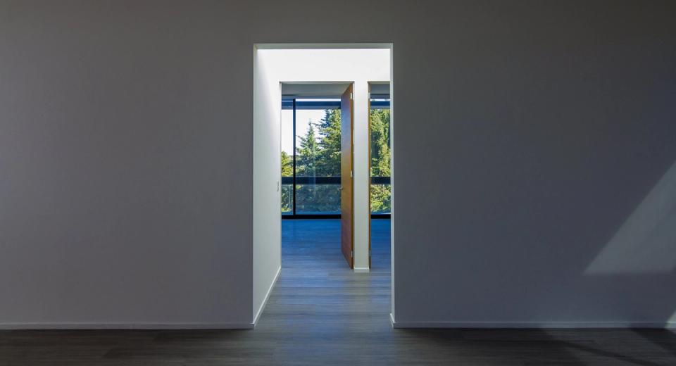 Vano que enmarca puertas de madera y ventanales hacia los árboles