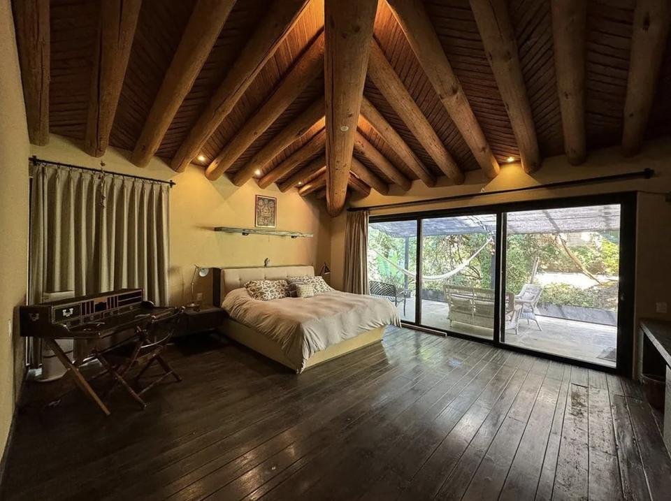 Recámara bajo vigas de madera con puertas de cristal hacia la terraza