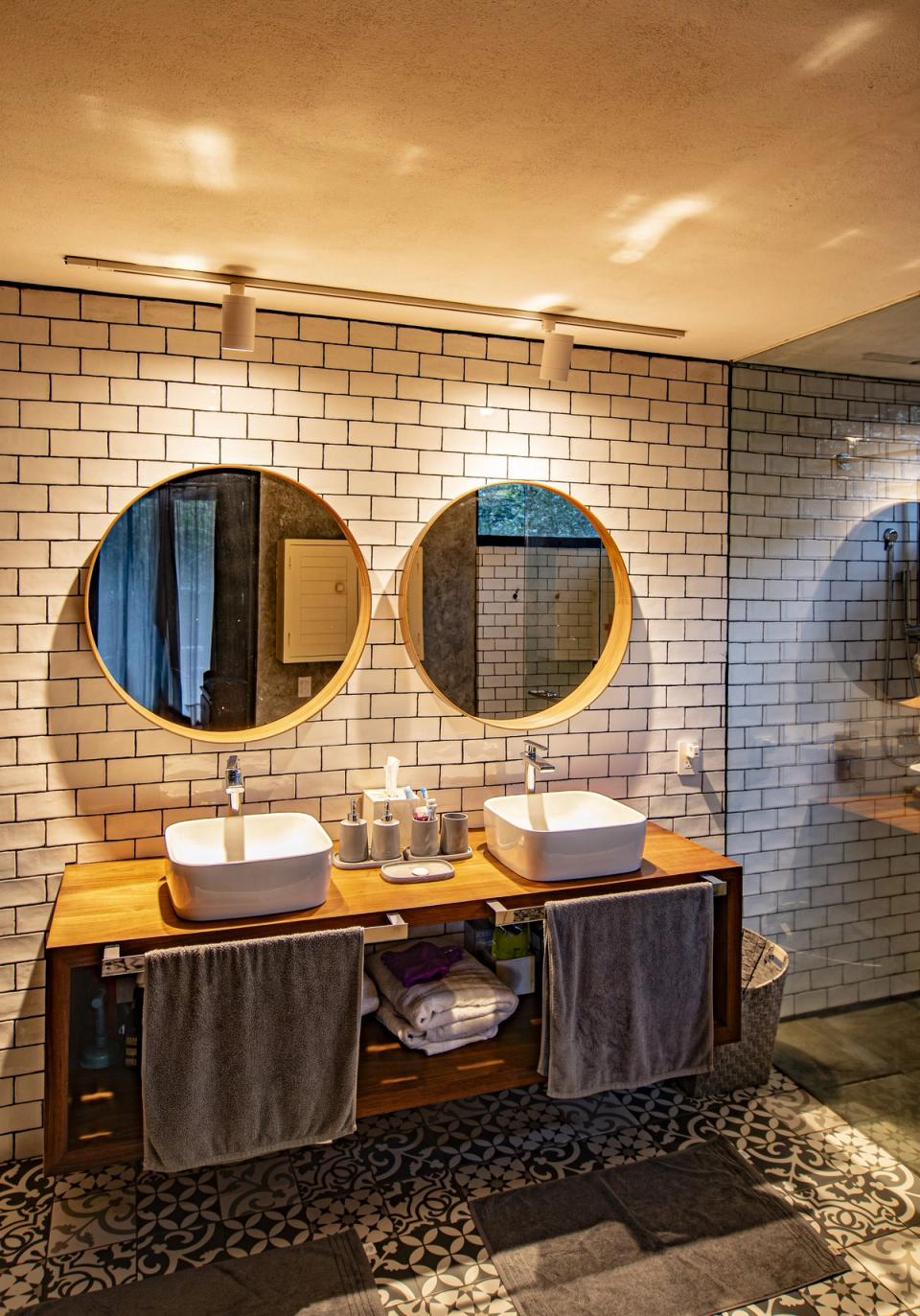 Baño con dos lavabos, espejos redondos y azulejo blanco