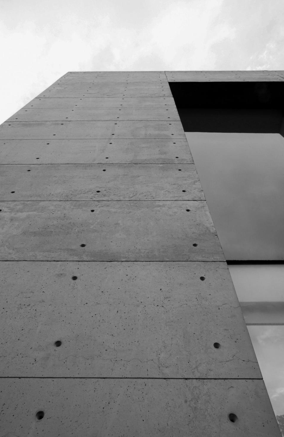 Muro de concreto aparente y ventanal vistos desde abajo, en blanco y negro