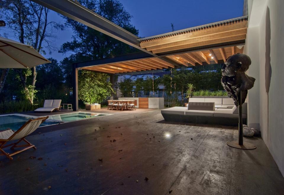 Terraza y comedor exterior bajo la pérgola iluminada de noche