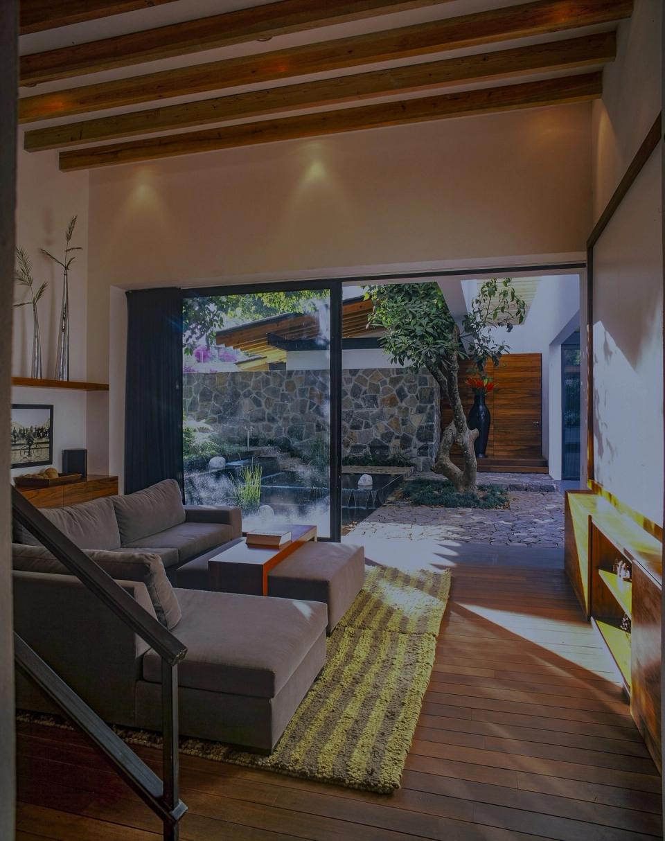 Sala con vigas de madera abierta al patio con muro de piedra