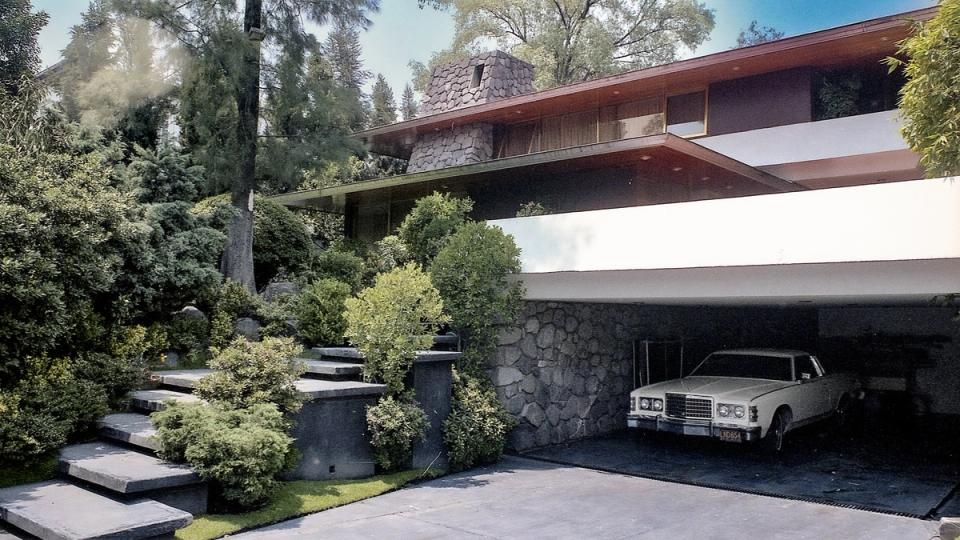 Casa con cochera abierta, jardín y escalones de piedra