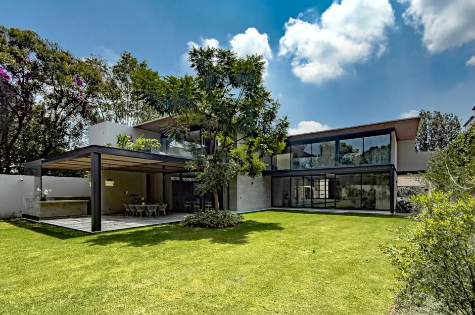 Casa Saratoga desde la calle, volúmenes claros y portón de madera