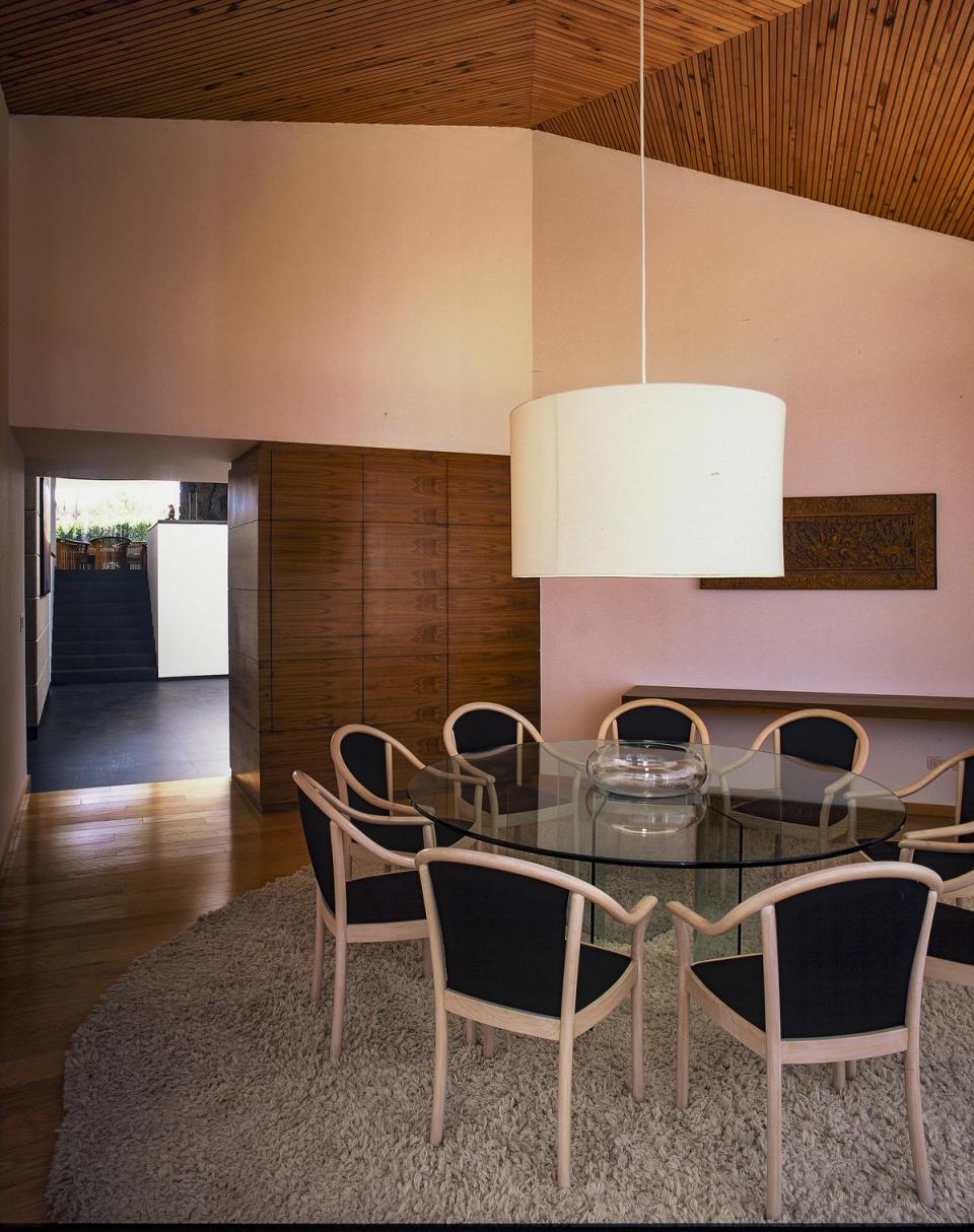Comedor con mesa redonda de cristal bajo el techo de madera