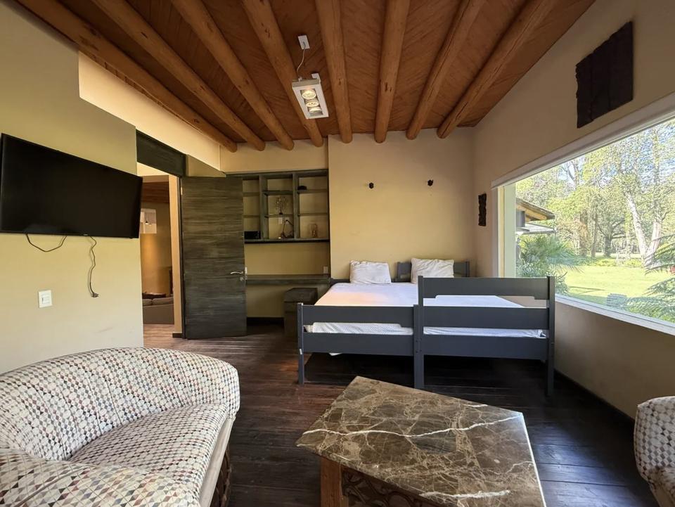 Recámara con sala y una ventana amplia hacia el jardín