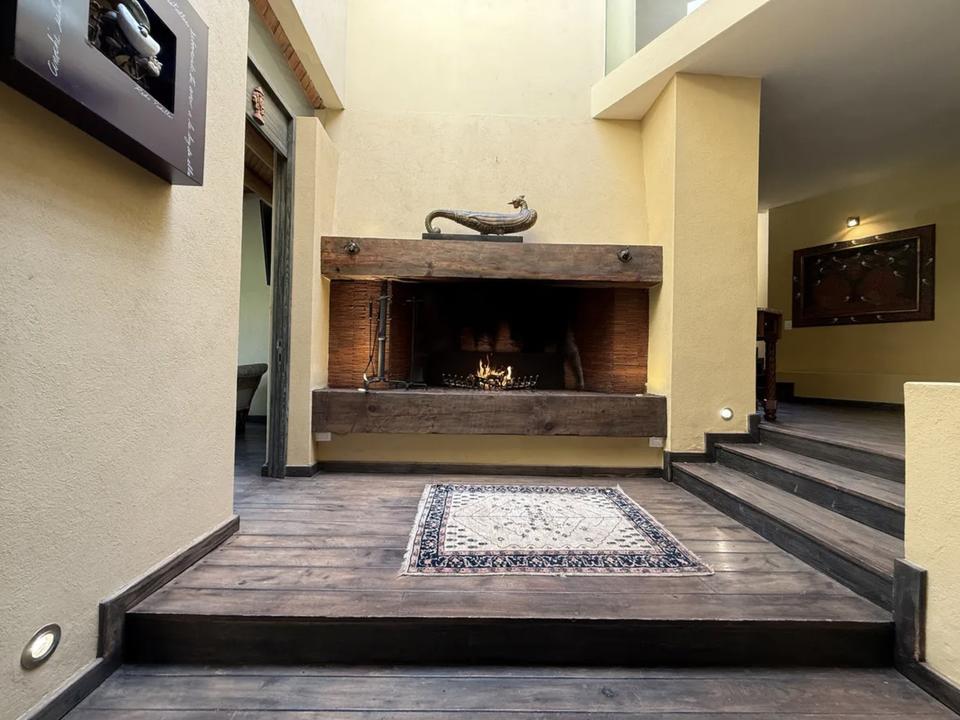 Chimenea con repisa de madera y escalones en un vestíbulo de doble altura