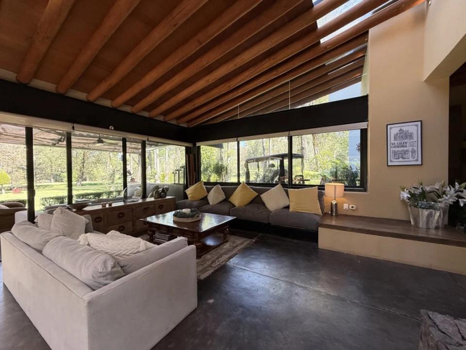 Sala con techo inclinado de vigas de madera y ventanas altas