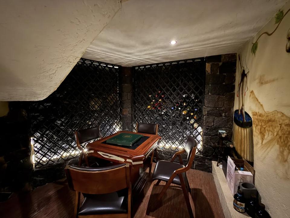 Cava con celosía para botellas, muro de piedra y mesa de juego