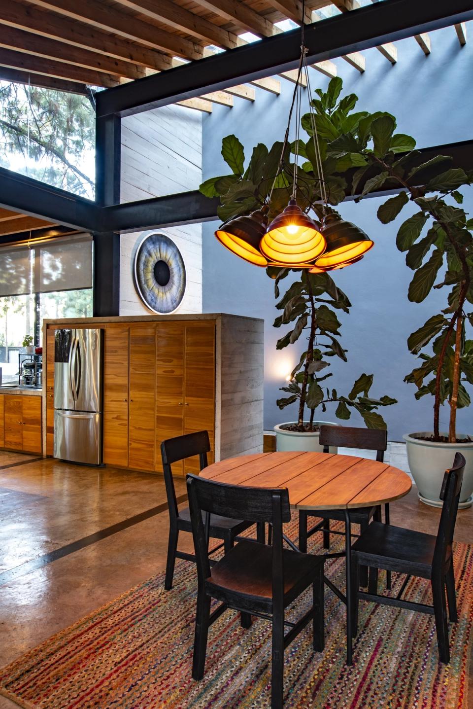 Mesa redonda junto a la cocina, con muro azul y plantas