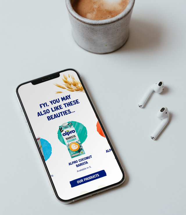 A smartphone displays an Alpro coconut barista product advertisement alongside a coffee cup and wireless earbuds on a white surface.