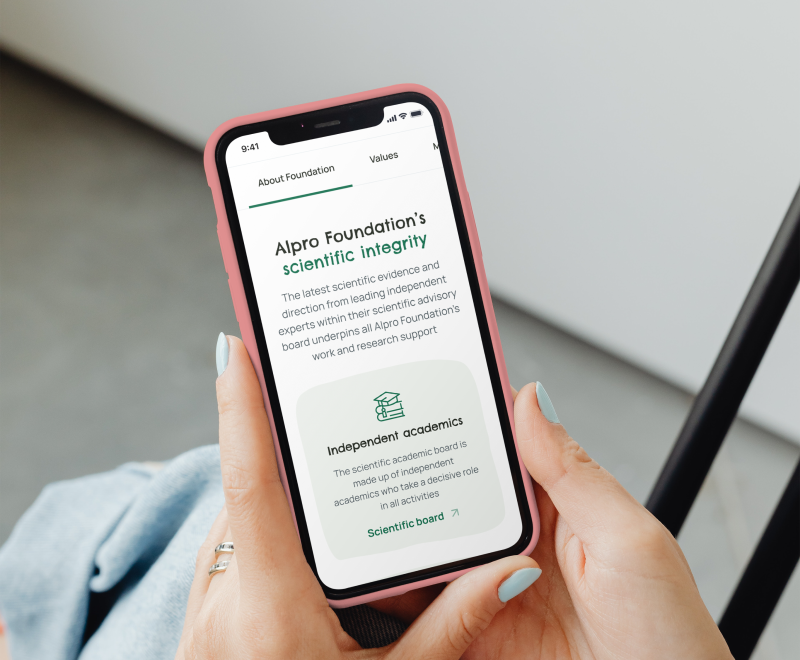 A pink iPhone displays the Alpro Foundation's scientific integrity page, showing information about their independent academic board and research support.