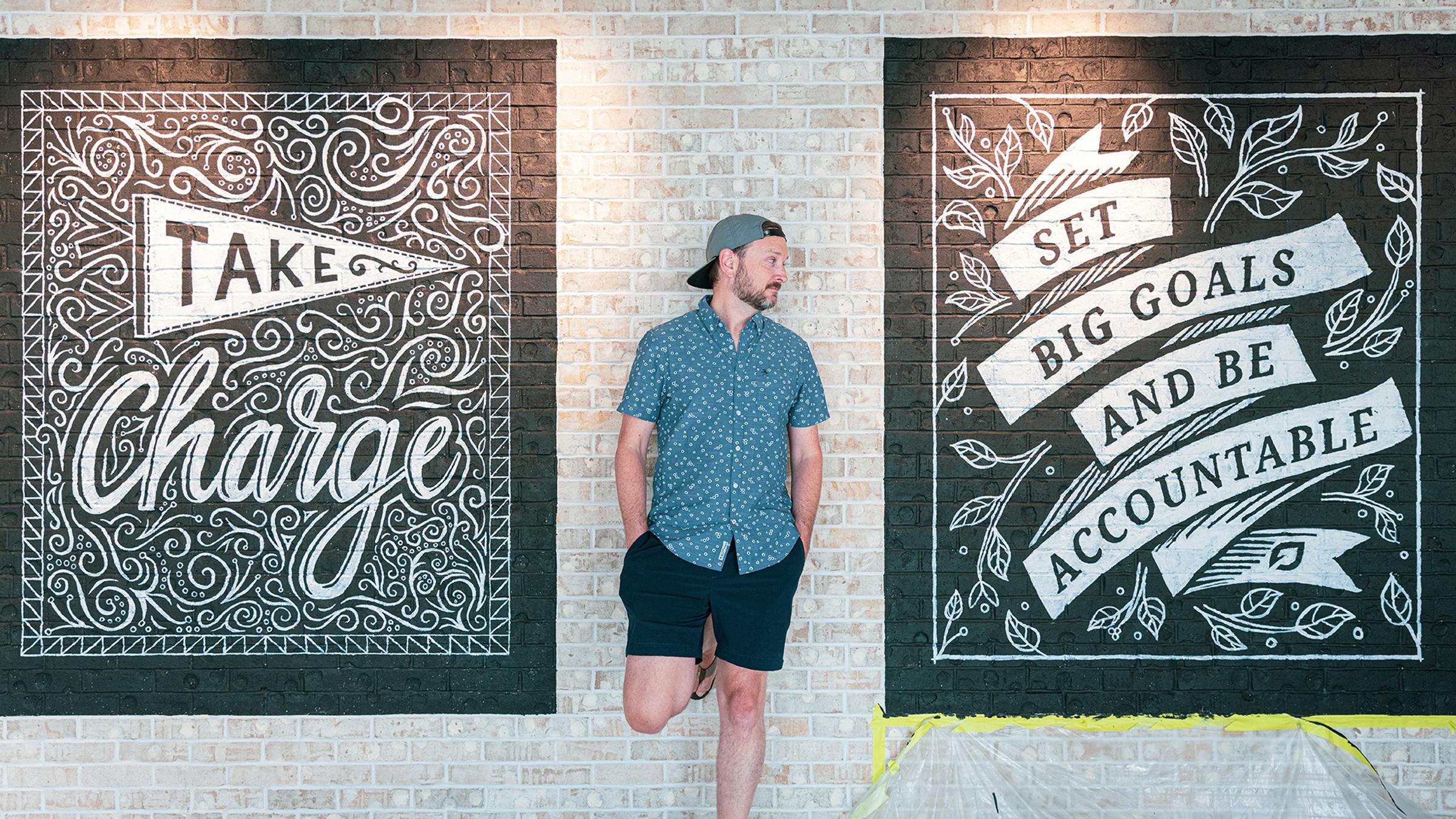Nate standing between two of his murals