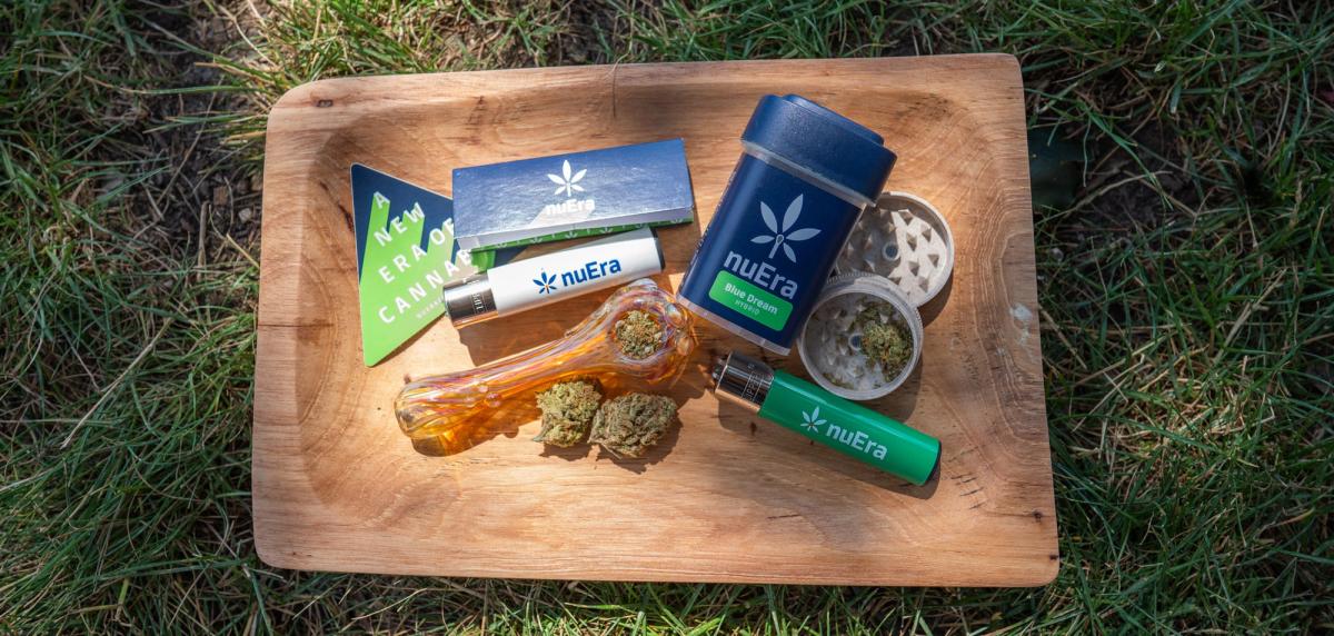 nuEra packaging, vape, grinder, and lighter on a wooden tray