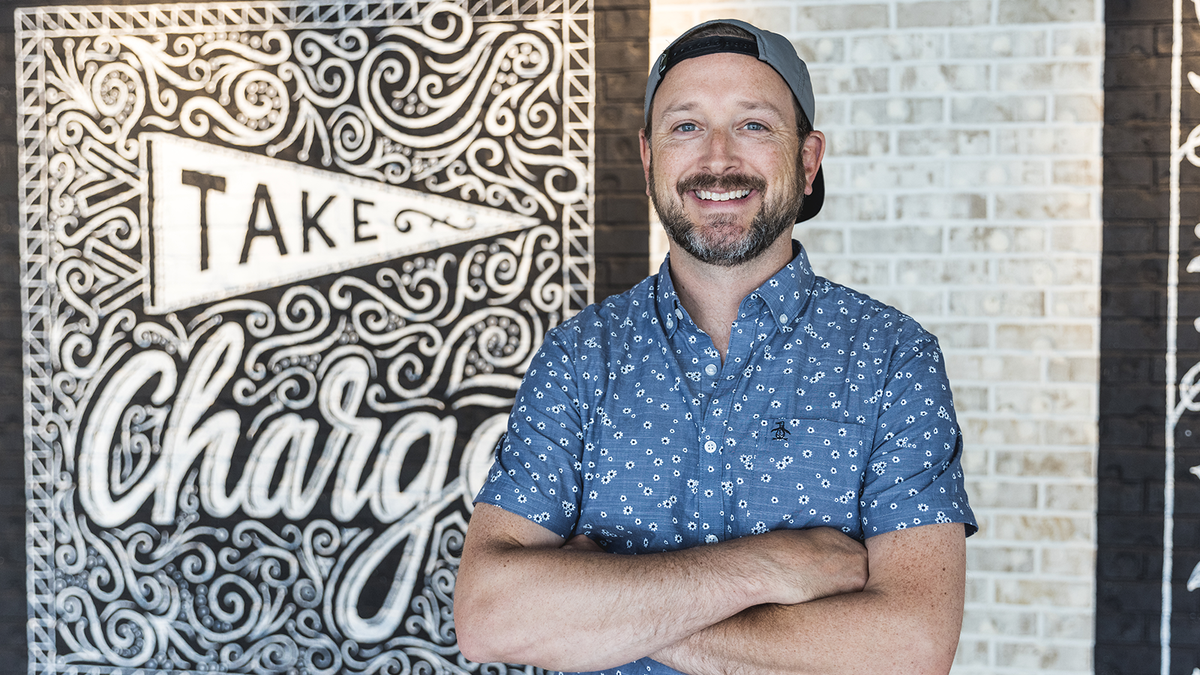 Nate Azark of 12 Line in front of the Take Charge mural he hand-lettered for LendingTree