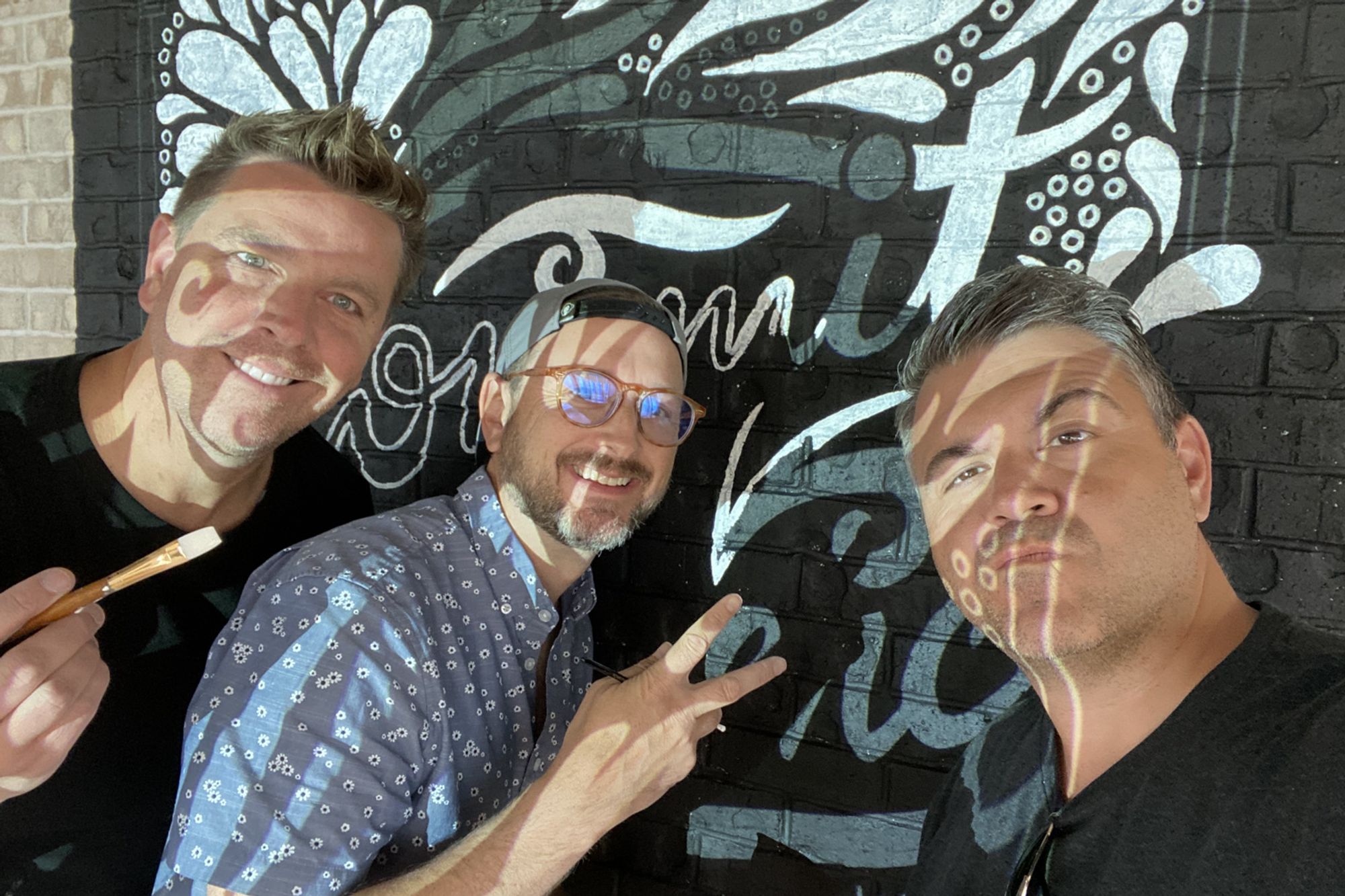 Nate, Todd Lauer, and Frate Iafrate in front of a lettered mural at LendingTree