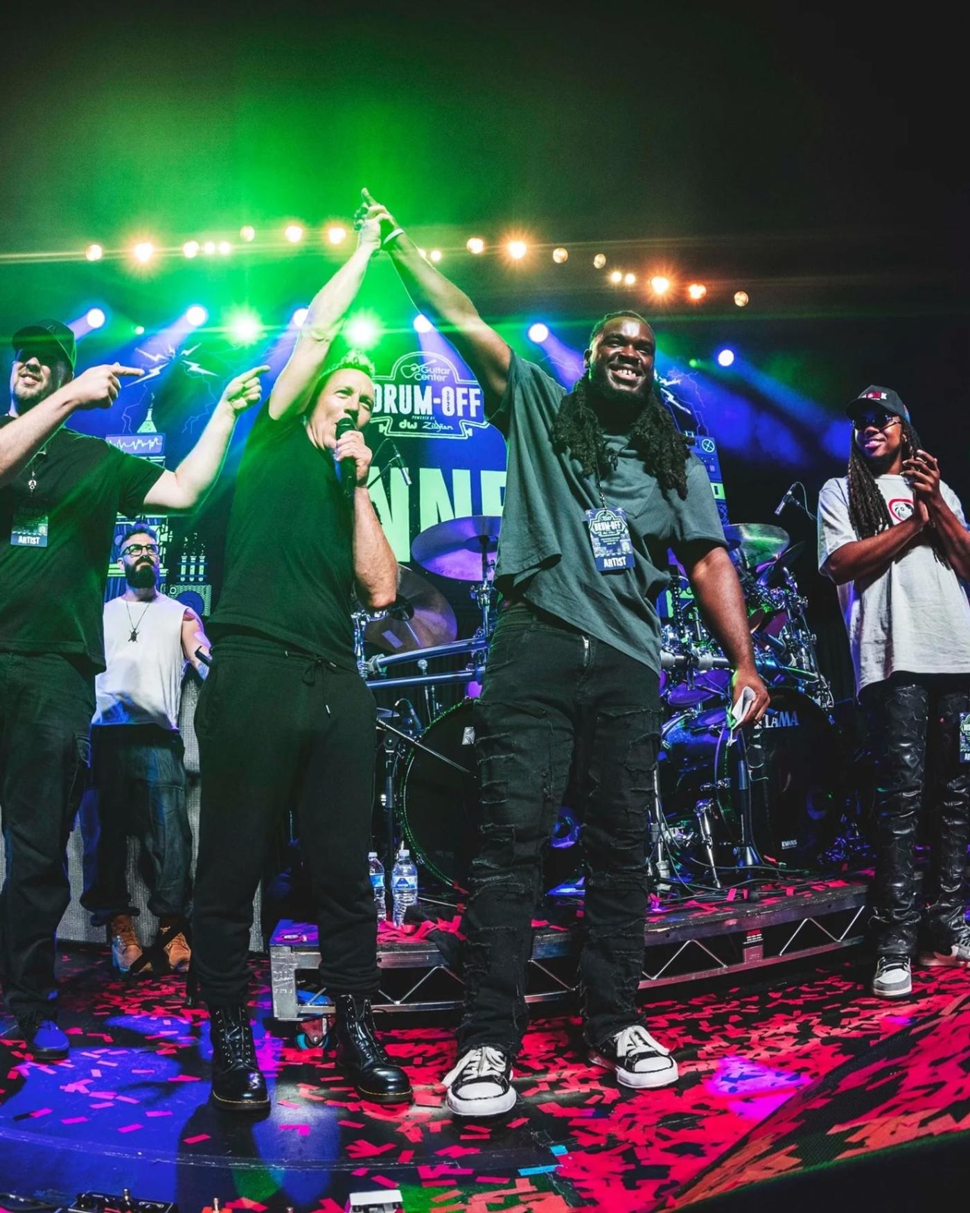 Performers celebrating on stage under green lights