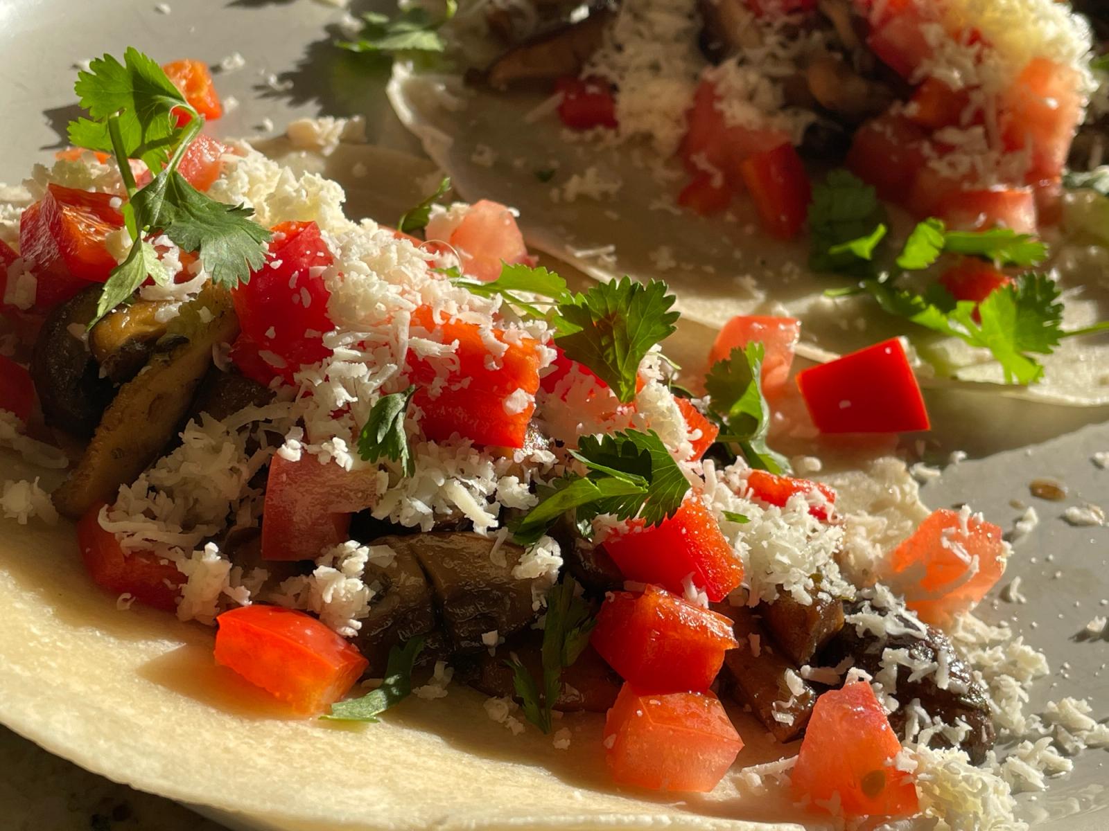 Homemade tacos topped with tomato, cilantro, and cheese