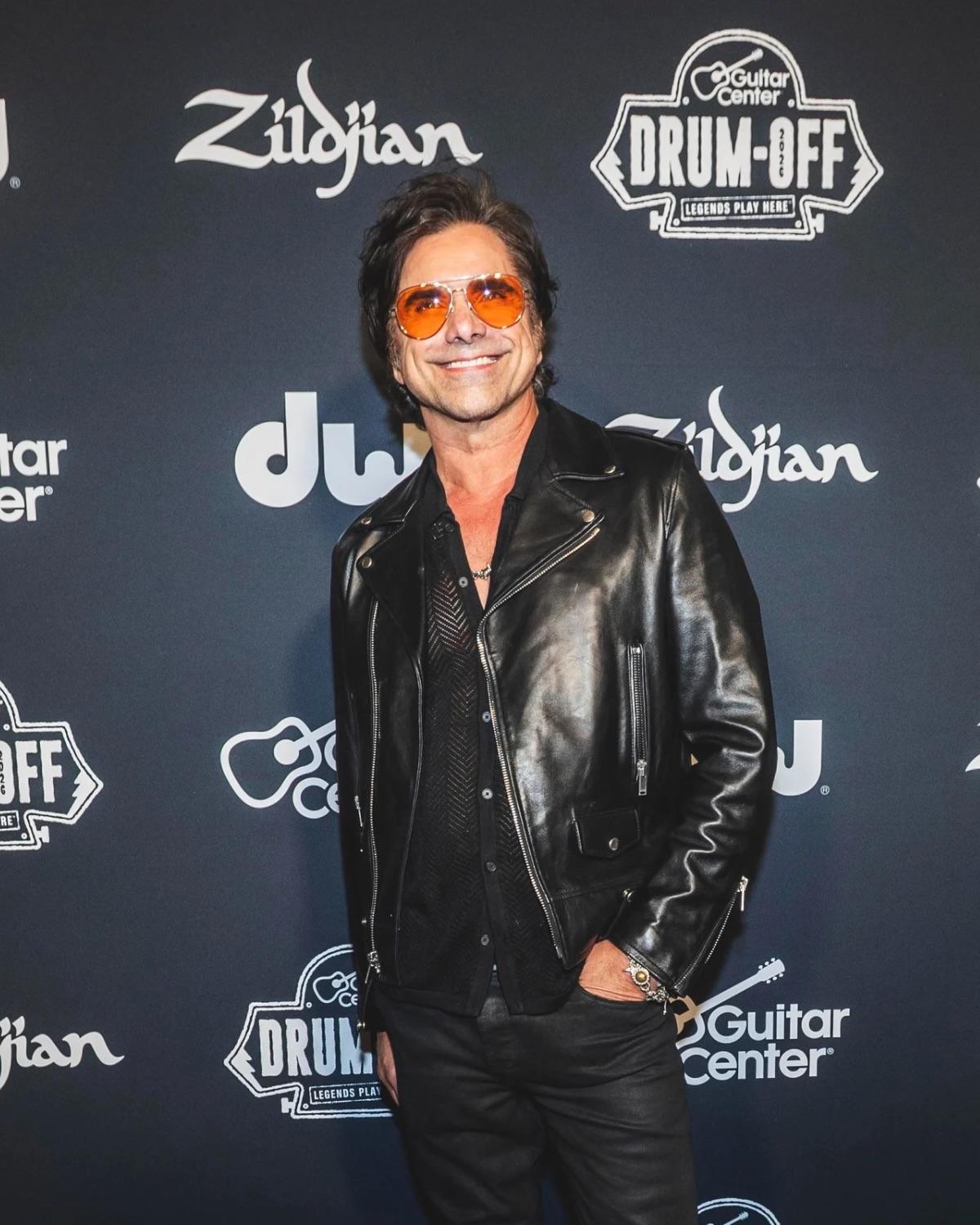 John Stamos on the red carpet in front of a Drum-Off, DW, and Zildjian step-and-repeat