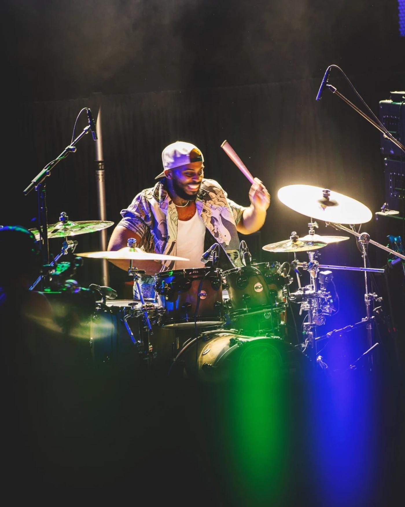 A drummer playing under blue stage light