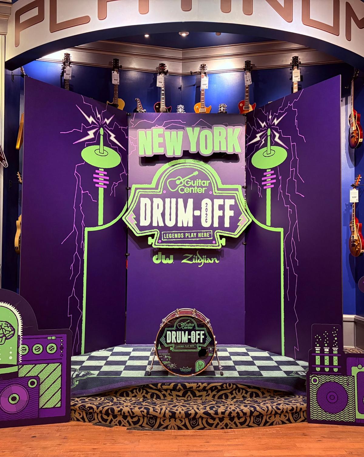The New York regional stage: a NEW YORK Drum-Off sign over a purple lab set with a checkered floor