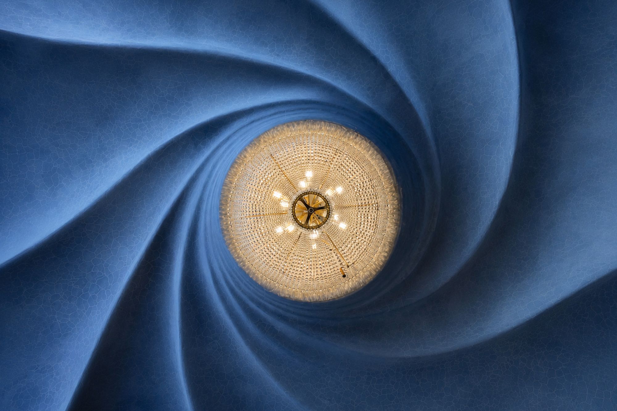 Looking up at the spiral ceiling and chandelier inside Casa Batlló, Barcelona